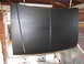 1987 Ford Bronco - A dark gray hood hangs in a garage, suggesting it is undergoing repair or painting.