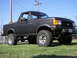 1987 Ford Bronco - This lifted Ford Bronco sits on a grassy lawn under a clear blue sky.