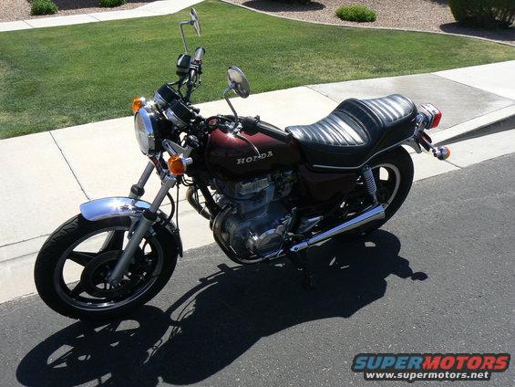 Maroon Honda motorcycle with chrome fender and black seat parked on asphalt