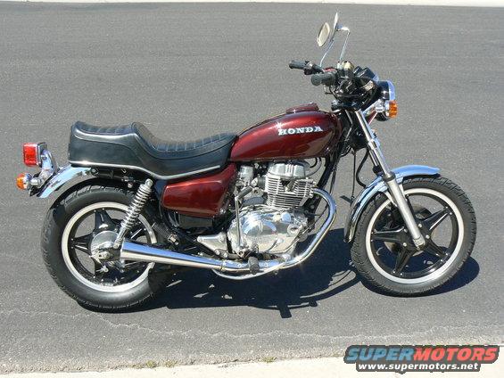Red Honda motorcycle parked on asphalt, side view