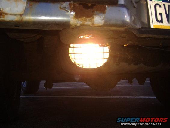 Underside view of a vehicle's rear bumper with a round light and a license plate that reads 'GV'