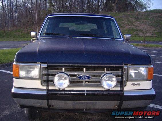 Blue and white Ford Bronco front view with aftermarket grille guard and fog lights