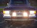 1988 Ford Bronco - Frontal view of a dark SUV, a brush guard with two large fog lights and a '4x4' badge.