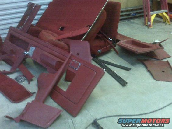 Pile of red car interior panels and seats on a concrete floor