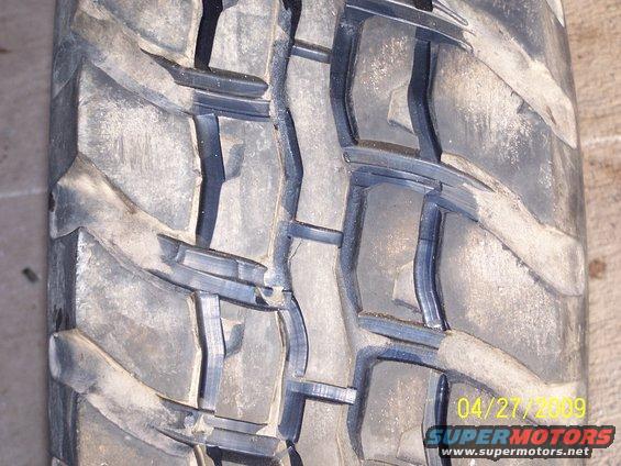 Close-up of a worn off-road tire tread with deep grooves and blocky patterns