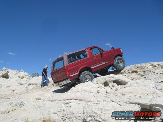 1993 Ford Bronco climbing rocks with a person standing nearby