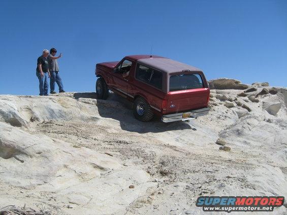 Red 1993 Ford Bronco off-roading on rocks