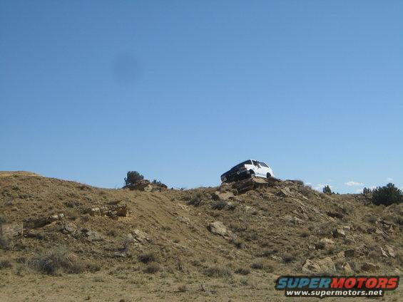 White SUV on rocky incline under clear blue sky