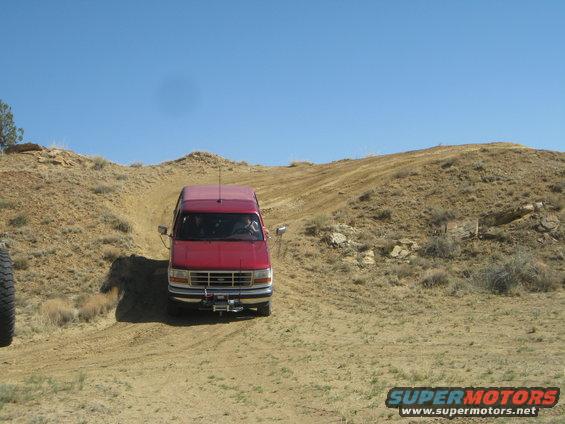 Red van with a winch driving on a dirt hill, 1993 model year suggested by grille