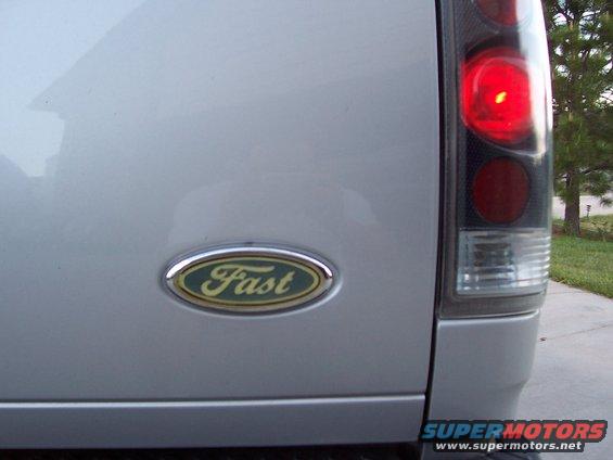 Close-up of a silver truck's rear with a 'Fast' emblem and illuminated tail light