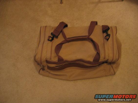 Tan duffel bag with brown trim and straps on carpet