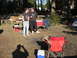 1979 Ford Bronco - A campsite scene with two men, camping chairs, coolers, and a tent set up in a wooded area.