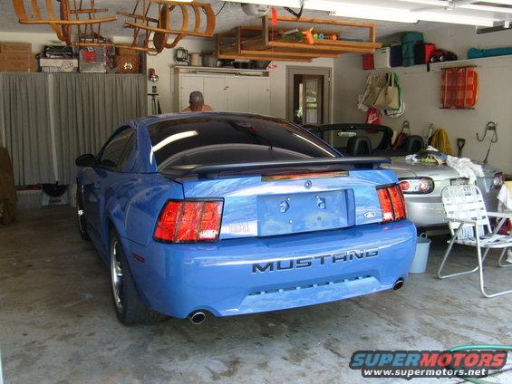 Blue Mustang in garage, silver convertible behind it. Sleds hanging from ceiling