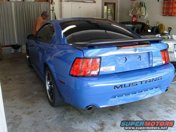 Blue Ford Mustang with a rear spoiler and "MUSTANG" badging on the bumper
