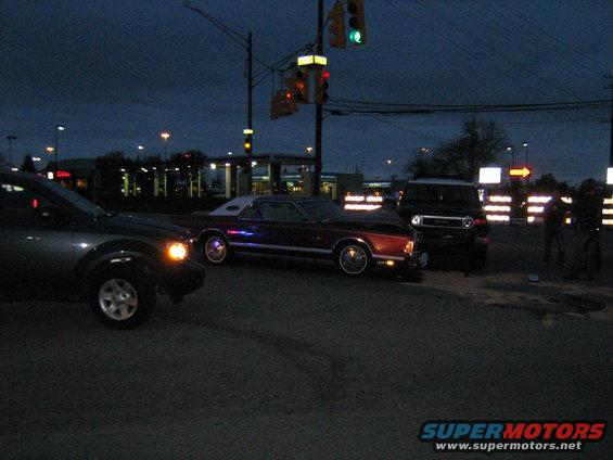 Maroon coupe with white vinyl roof, side view, at dusk