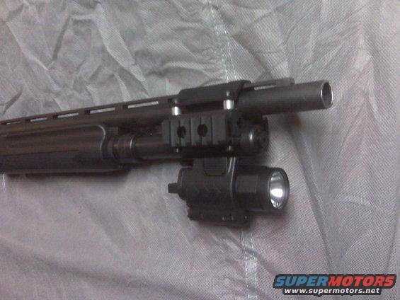 Shotgun barrel with a tactical flashlight mounted to a rail system