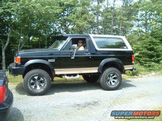1991 Ford Bronco parked on gravel with trees in background
