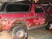 1978 Ford Bronco - This heavily rusted red Ford Bronco is in a garage, showing significant body damage.