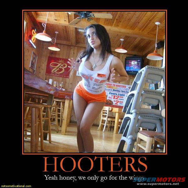 Woman in white tank top and orange shorts stands in a Hooters restaurant