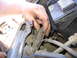 1987 Ford Bronco - A hand manipulates wiring within the engine compartment, near the battery terminals.
