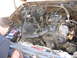 1987 Ford Bronco - A mechanic works on the battery in the engine bay of an older model vehicle.