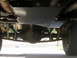 1996 Ford Bronco - Underside view of a vehicle's rear suspension and differential, a skid plate and aftermarket shocks.