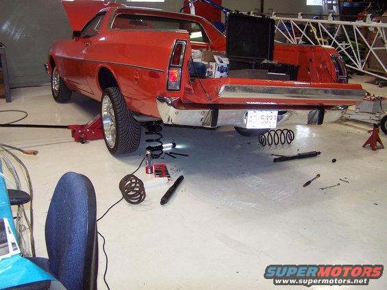 100_2554.jpg replacing the rear coil springs; the shocks have been removed and the the vehicle gets jacked up until the coils fit; then lower it and re-install the shocks; pretty easy, actually.