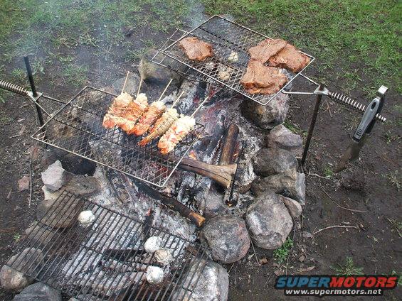 Campfire cooking steaks and shrimp skewers on grills