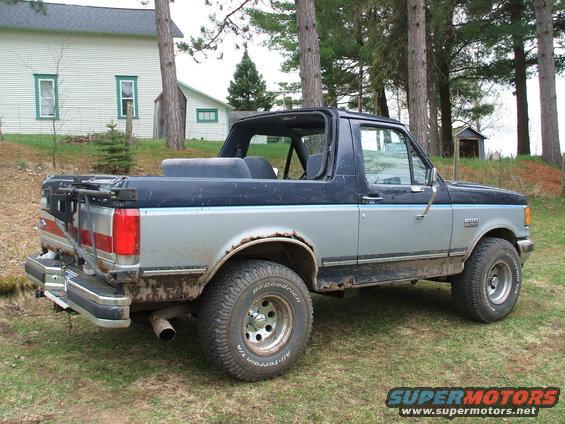 Two-tone blue and silver Ford Bronco with a removable top, showing rust on the rear fender