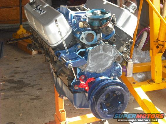 V8 engine with blue block and silver valve covers on an orange engine stand. Summit Racing logo visible on valve cover