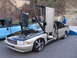 2001 Chevrolet Silverado 1500 - Modified sedan with custom doors and wheels, parked next to a blue pickup truck.