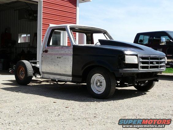 Unfinished 1994 Ford F-150 with a black hood scoop and bare metal body panels