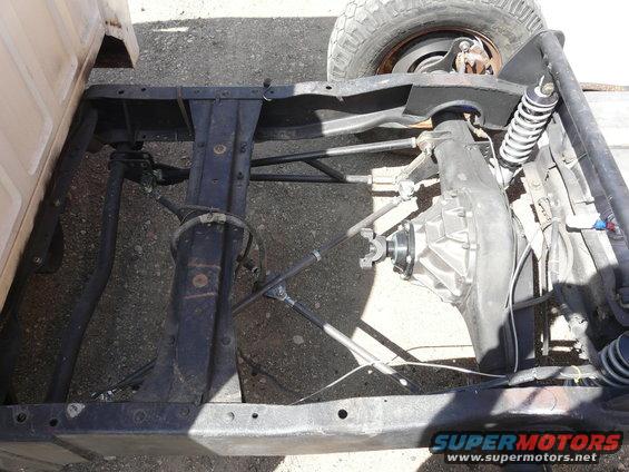 Truck frame with rear axle, suspension, and part of a tire visible. Some brake lines and wiring are also shown