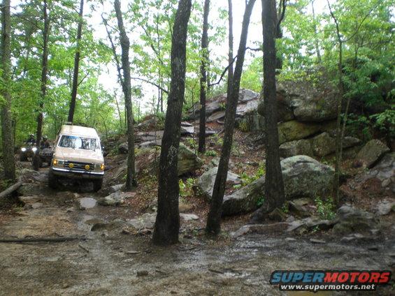 Tan van and ATV on rocky forest trail