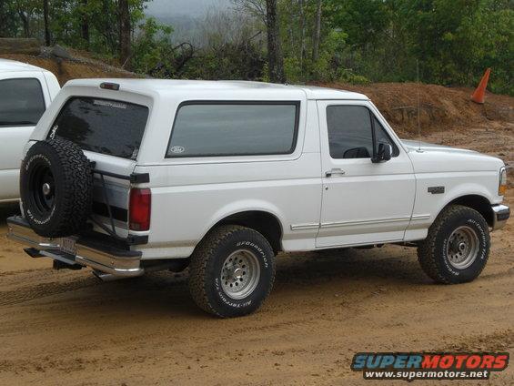 White Ford Bronco with spare tire on rear, parked on dirt road