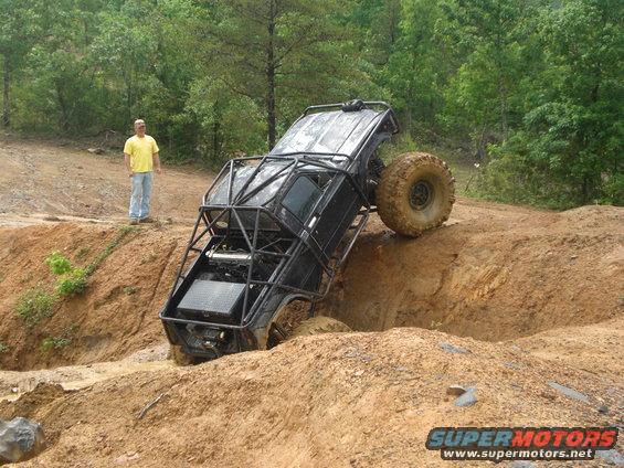 Off-road vehicle with roll cage tilted on muddy terrain