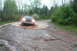 1995 Ford Bronco - A dark-colored Ford Bronco navigates a water-filled rut on a wet, wooded road.