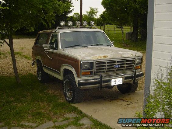 Ford Bronco with wood paneling and roof-mounted lights, parked on a driveway
