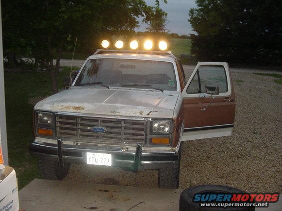 1980s Ford Bronco with a light bar on the roof and the driver's door open. License plate reads YCQ 22X