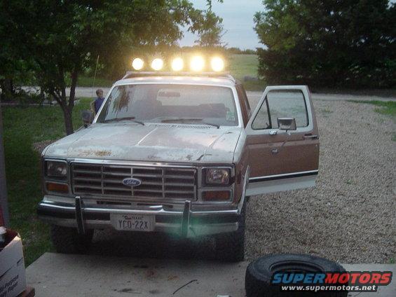 Ford Bronco with roof lights and open door, parked outside