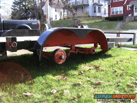 Black pickup truck towing a trailer with red fenders and two axles