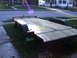 2005 Ford F-250 - A utility trailer with a wooden deck is parked on a residential street.