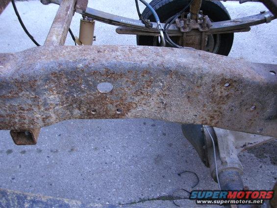 Rusted truck frame section with leaf springs and shock absorber visible