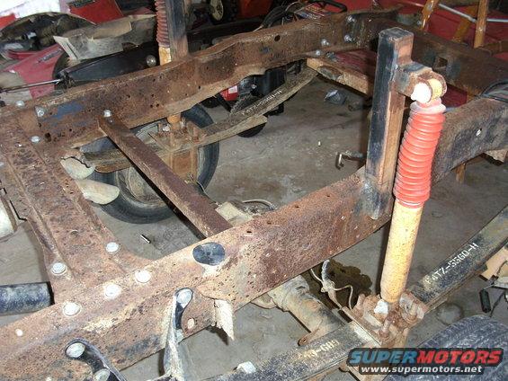rusted truck frame showing leaf springs and shock absorber