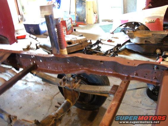 Truck frame and suspension parts in a garage. Some rust visible on the frame