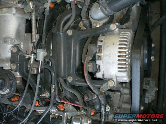 Engine bay shot showing alternator, belts, and various hoses and wires