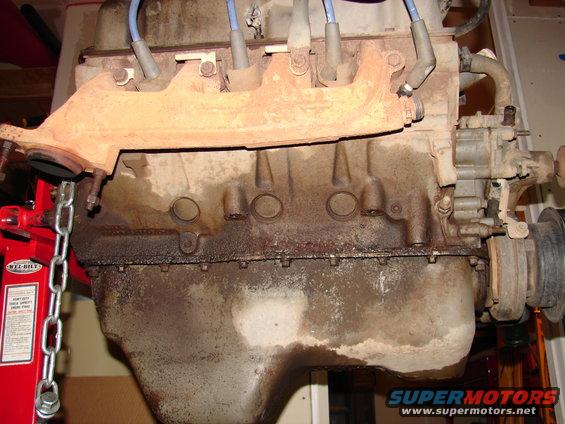 Engine block with exhaust manifold attached, showing oil leaks
