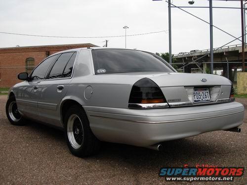 Silver sedan with aftermarket wheels and tinted taillights, viewed from the rear quarter