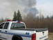 1996 Dodge 2500 - A white pickup truck marked "Peace Officer" is parked near a scene with a large plume of smoke rising from trees in the distance.