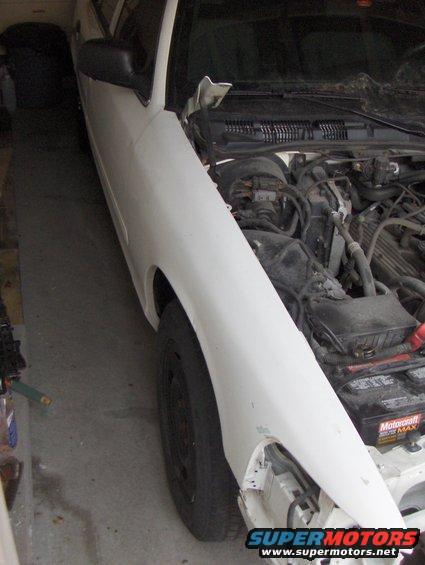 2003 Ford Crown Victoria front fender and engine bay with hood open. Battery visible